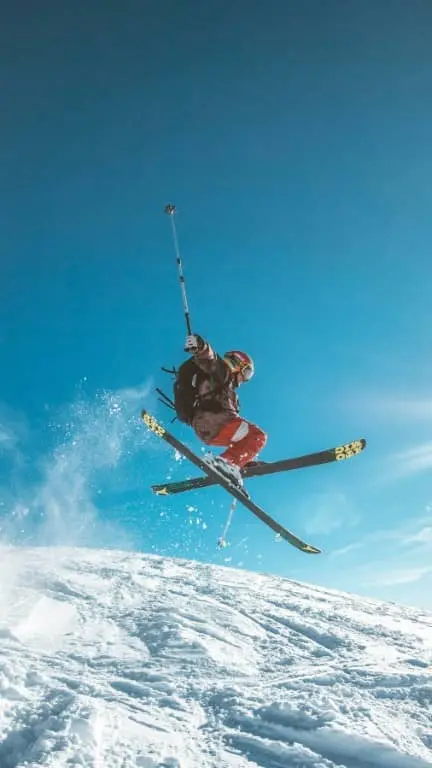 skier in the air with his skis crossed with blue skies behind him